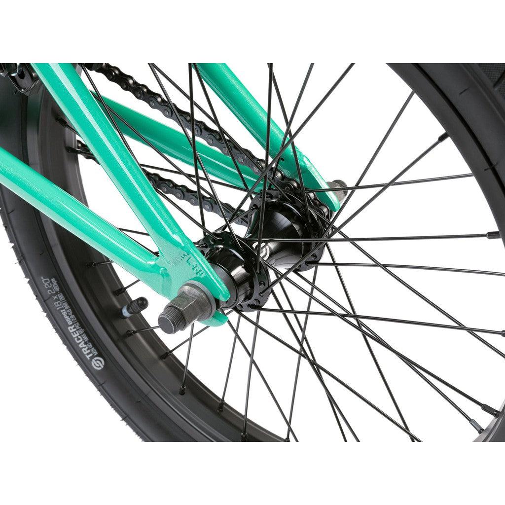 Close-up of the rear wheel and hub of a Wethepeople CRS FS 18 Inch green BMX bike, displaying spokes and part of the tire.