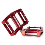 Red Stay Strong PIVOT Junior Platform Pedals with a flat platform design and multiple pins for grip. Both pedals, crafted using CNC machining, feature the words "STAY STRONG" printed in white.