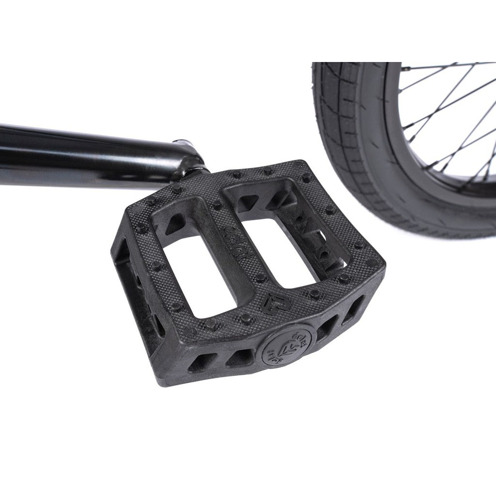 A close-up of a black pedal and crank arm on the Wethepeople CRS FS 18 Inch BMX Bike, with part of the tire visible, encapsulating the spirit of a freestyle BMX bike.