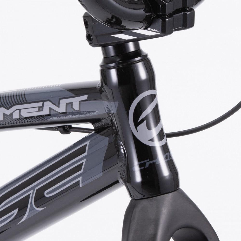 Close-up view of a black Chase Element Pro XXL bike frame, focusing on the head tube area with brand decals and part of the handlebar stem visible, complemented by sleek Ikon carbon forks.