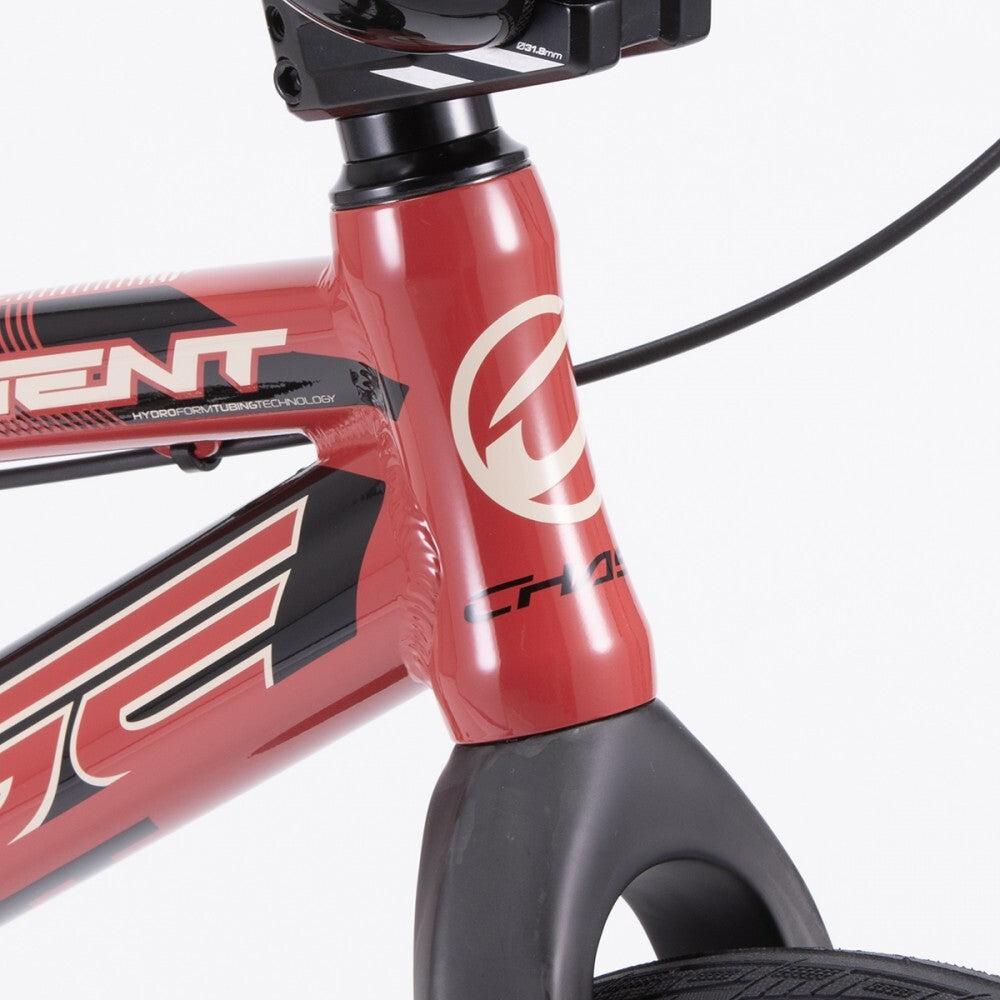 Close-up of a red Chase Element Expert Bike frame with black and white graphic details and a visible tire. The image shows the front part of the bike, including the handlebars, Ikon carbon forks, and brand logo.