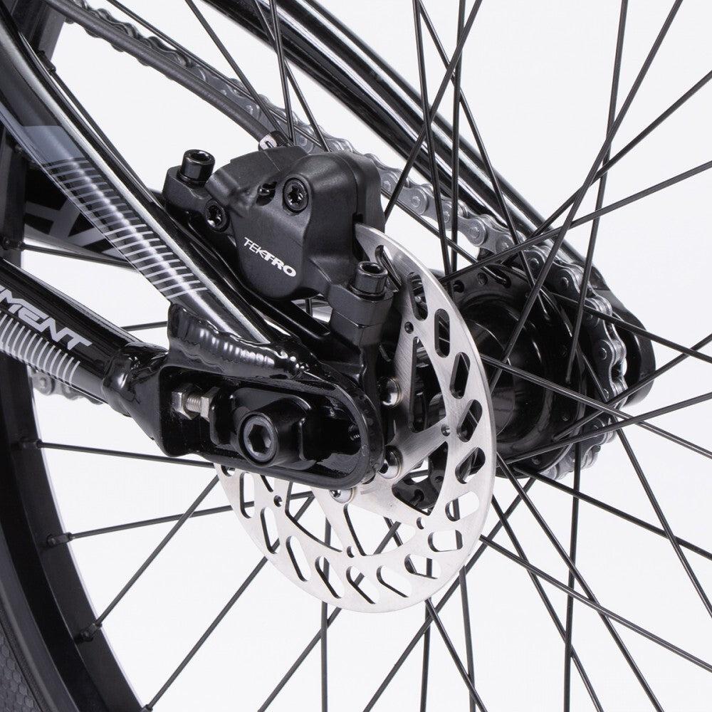 Close-up of the Chase Element Pro Cruiser bike's rear wheel showing the disc brake mechanism with a Tektro caliper, rotor, and spokes on an Expert XL frame.