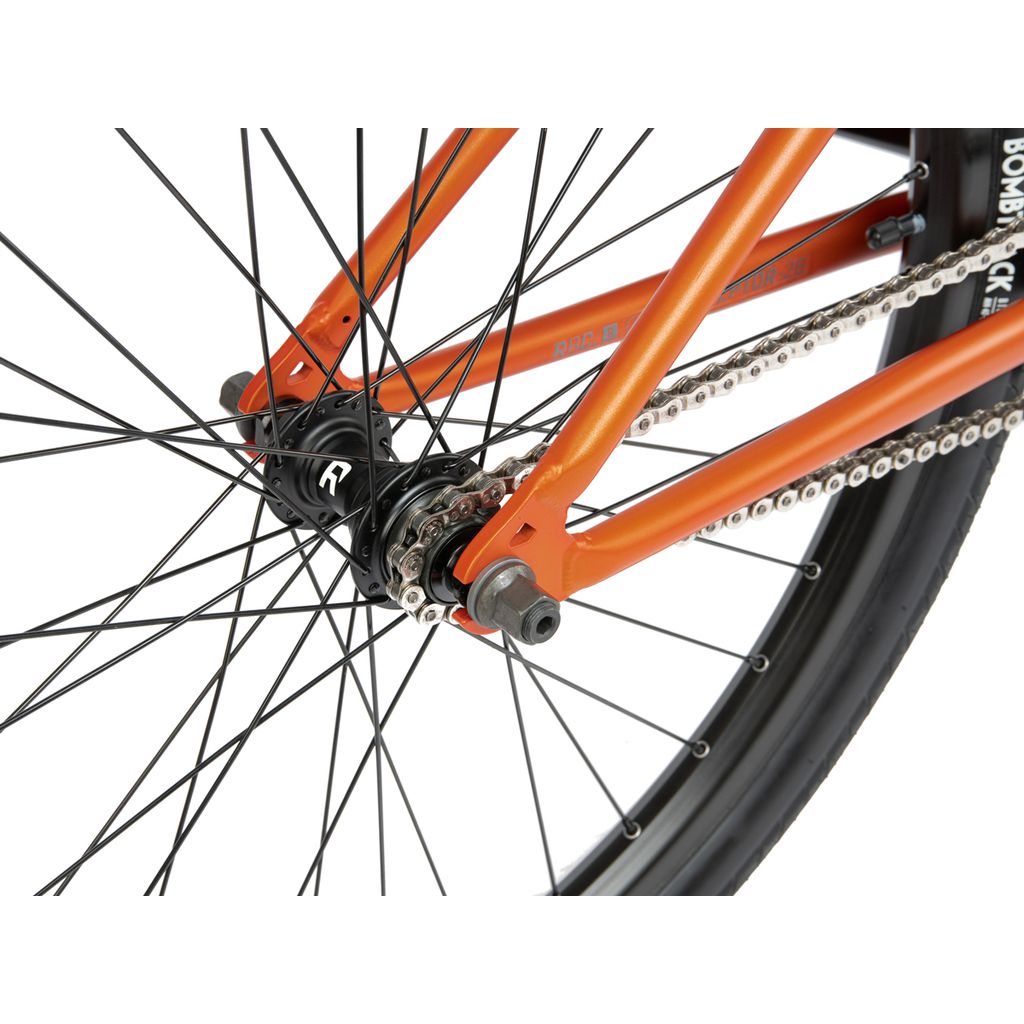 Close-up of the rear wheel and chain mechanism of an orange 26-inch BMX bike, focusing on the hub, spokes, and chainring. The Radio 26 Inch Ceptor Bike features sealed bearings for a smooth ride.