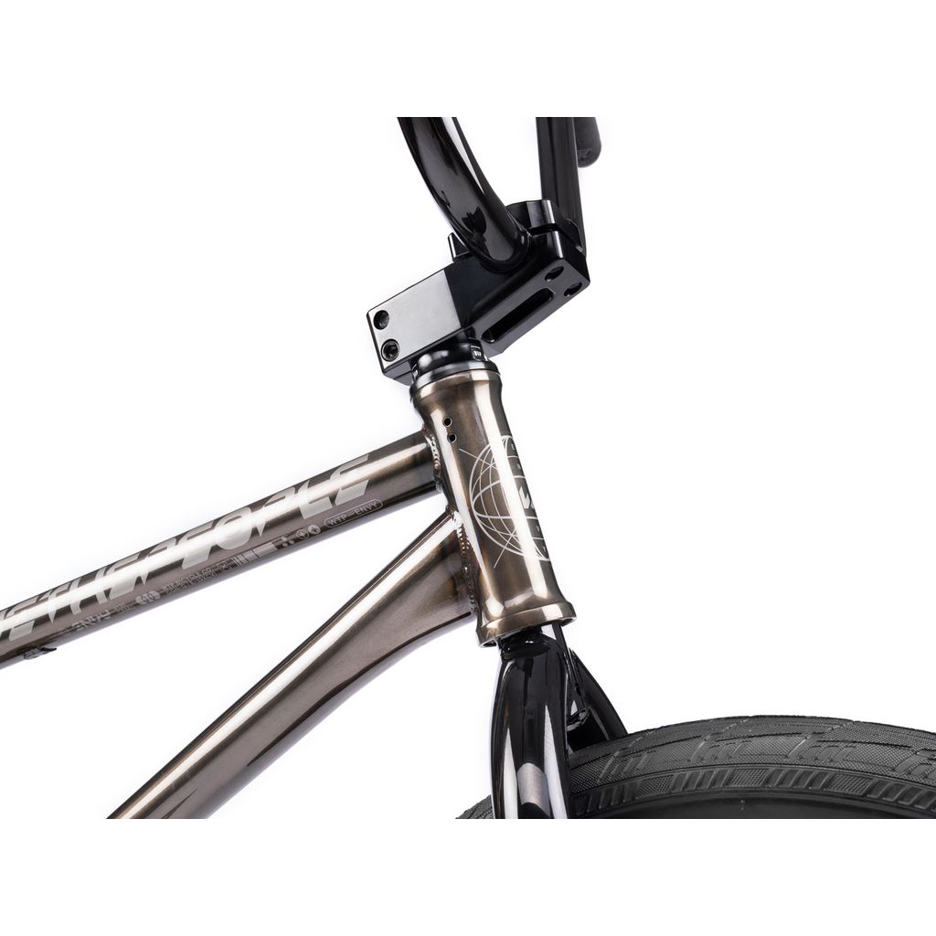 Close-up of a BMX's front frame, showcasing the metallic head tube with a logo. The black handlebars and part of the front tire highlight the sleek design, epitomizing the style of a Wethepeople Envy 20 Inch BMX Bike.