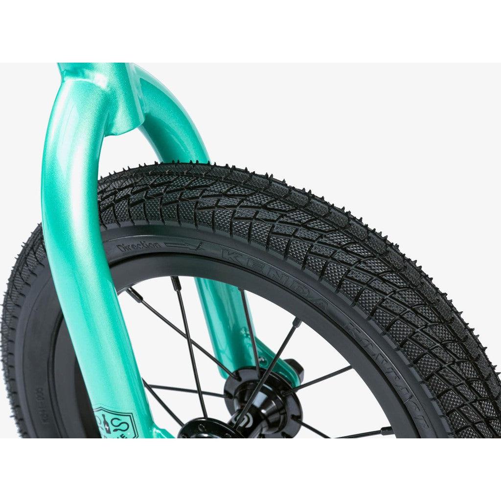 A close-up of a turquoise Wethepeople Prime Balance BMX bike fork paired with a black tire featuring a textured tread pattern. Set against a white background, this stylish balance bike offers a sleek and modern design, ideal for pre-order.