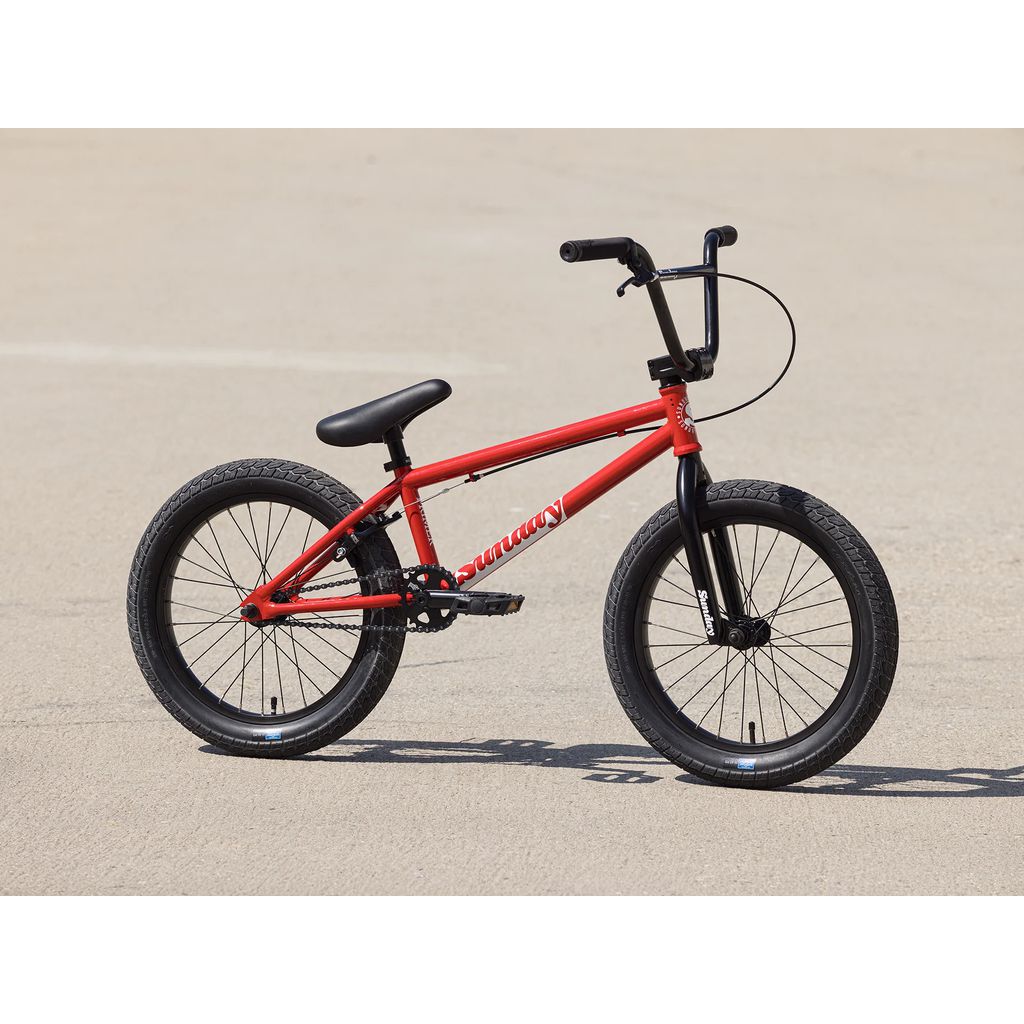 A Sunday Primer 18 Inch Bike (2025) in red with black handlebars and wheels, featuring Pro-Style geometry and Odyssey Springfield brakes, standing on a concrete surface.