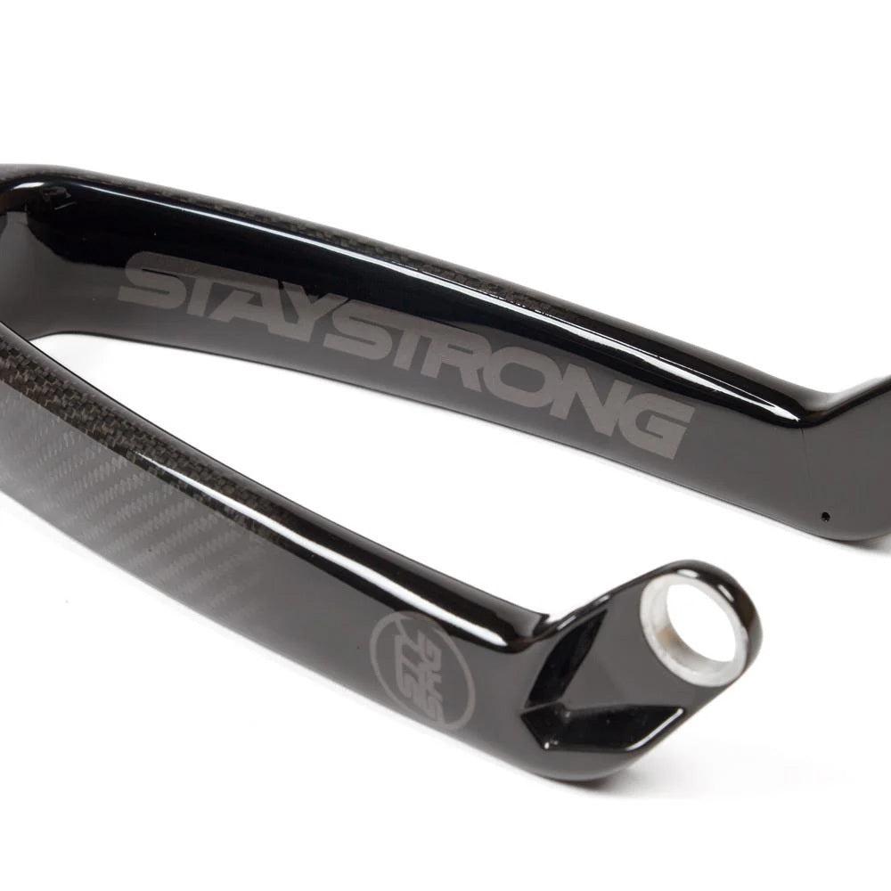 Close-up of an Avian-Staystrong Versus Pro Tapered 20 inch bike fork showcasing a sleek black frame with "STAY STRONG" emblazoned on it, complemented by lightweight carbon forks.