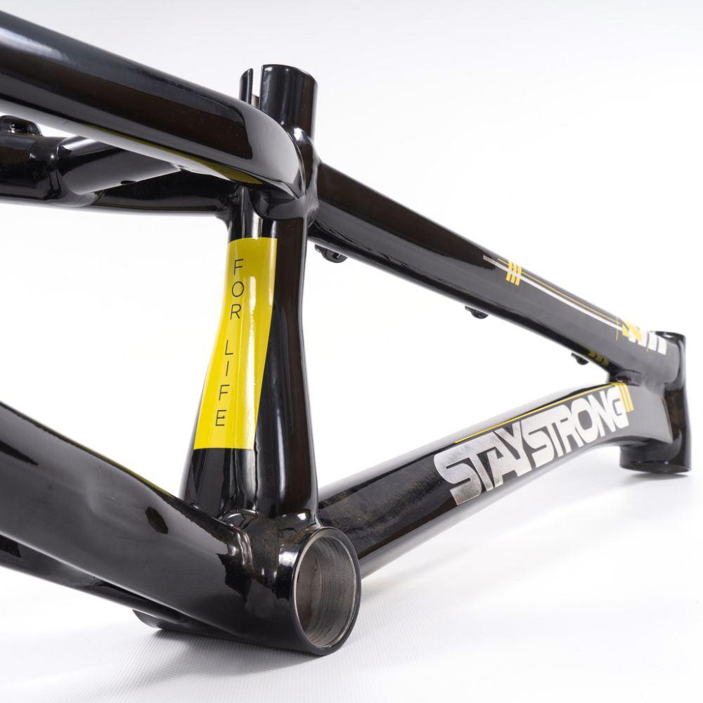 Close-up of a black Staystrong V4 Frame Expert XL Cruiser with yellow accents and the text "STAY STRONG" and "FOR LIFE" printed on it, positioned horizontally on a white background.