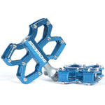 Blue Stay Strong Axis Junior Platform Pedals with a cross-shaped design and multiple attachment points, made from durable alloy extrusion CNC and featuring sealed bearings, shown on a white background.