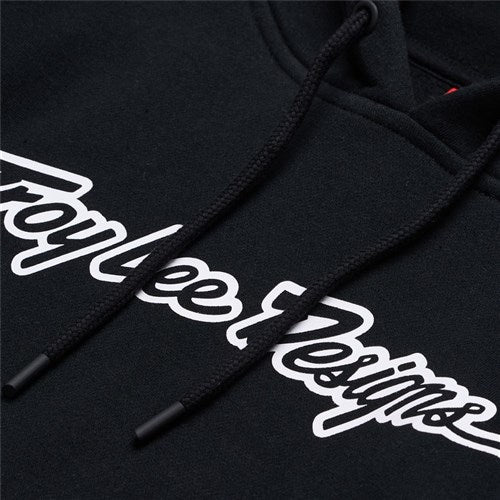 Close-up of the TLD 25.1 Signature Pull Over Hoodie, a stylish black pullover with "Troy Lee Designs" in white script on the chest and matching drawstrings, perfect for adding a touch of TLD flair to your wardrobe.