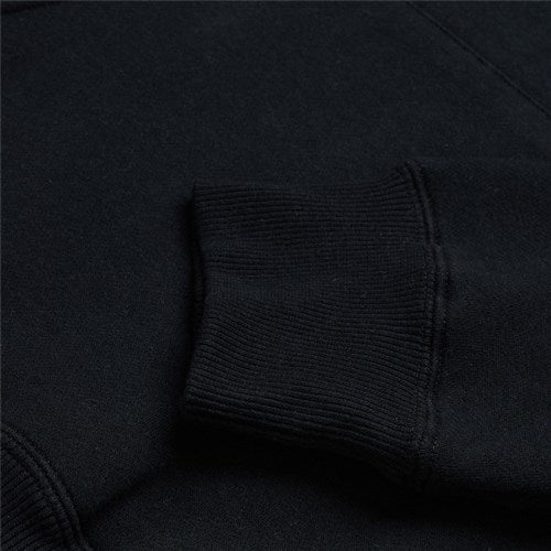 Close-up of a sleeve from the TLD 25.1 Signature Pull Over Hoodie in black, featuring a ribbed cuff on a textured background; a timeless wardrobe addition.