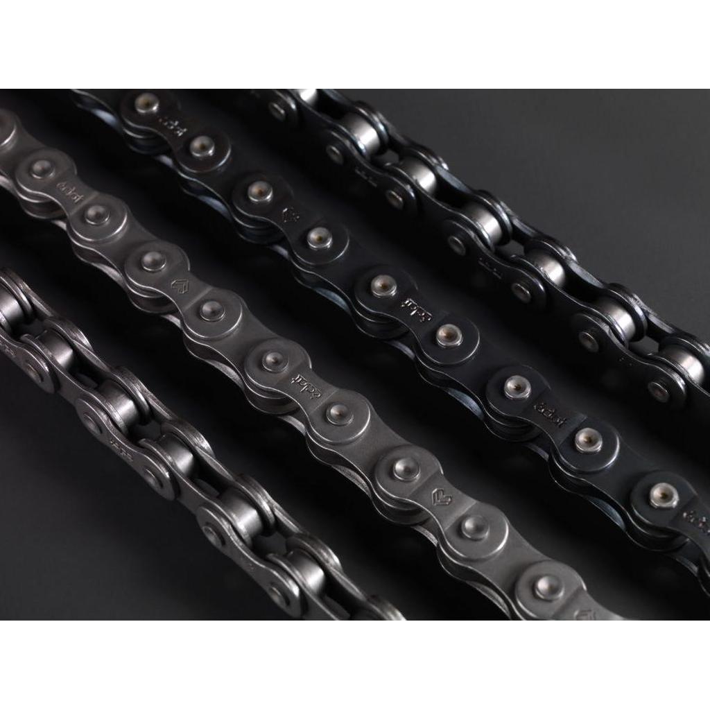 A close-up showcases four durable Eclat Diesel Chains, resembling motorbike styles, laid parallel on a dark surface, highlighting their links and pins in detail.