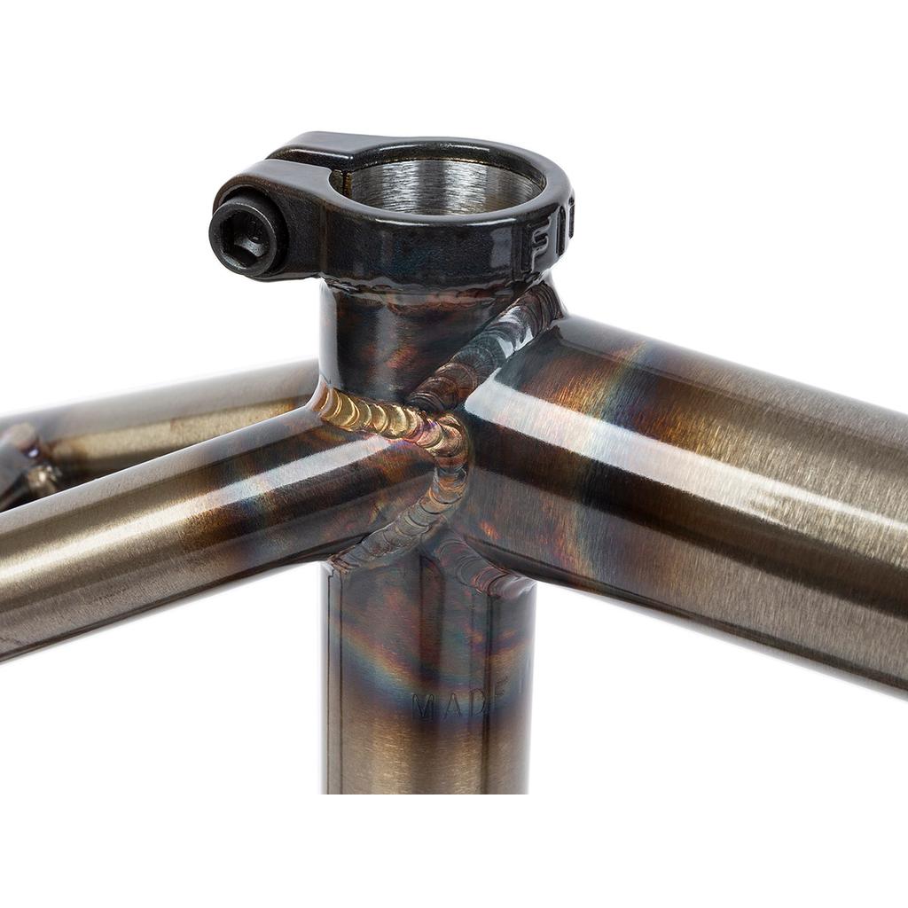 A close-up of the Fit Bike Co Sleeper (Ethan Corriere) Frame junction reveals welded joints and a seat clamp, with multicolored heat treatment patterns on its American-made metal surface, showcasing fine craftsmanship.