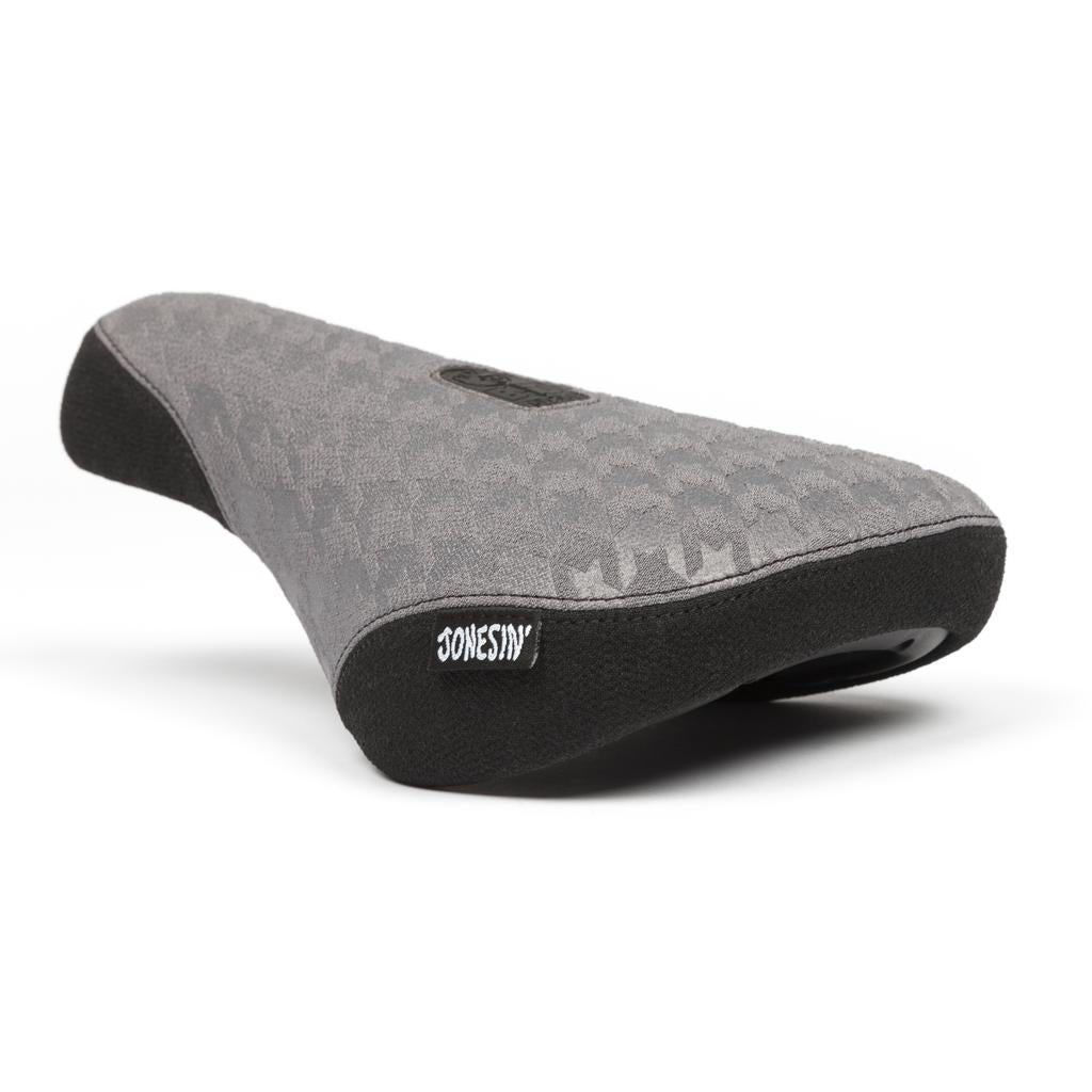 A grey BSD Jonesin Pivotal Seat with a textured pattern, durable Kevlar bumpers, and a black label featuring "Jonesin'" in white text on the side.