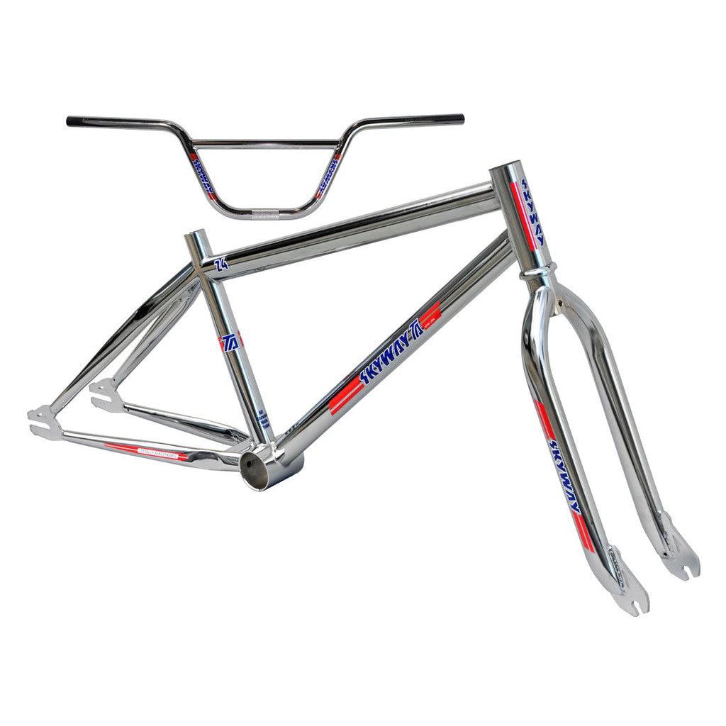 A shiny silver Skyway TA 24 Replica Frame / Fork / Bars Kit with Chromoly Teardrop Tubing and blue and red decals, displayed on a white background.