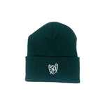 The S&M Sharpie Shield Beanie is a green knit hat made from hypoallergenic acrylic, featuring a white embroidered shield emblem on the front.