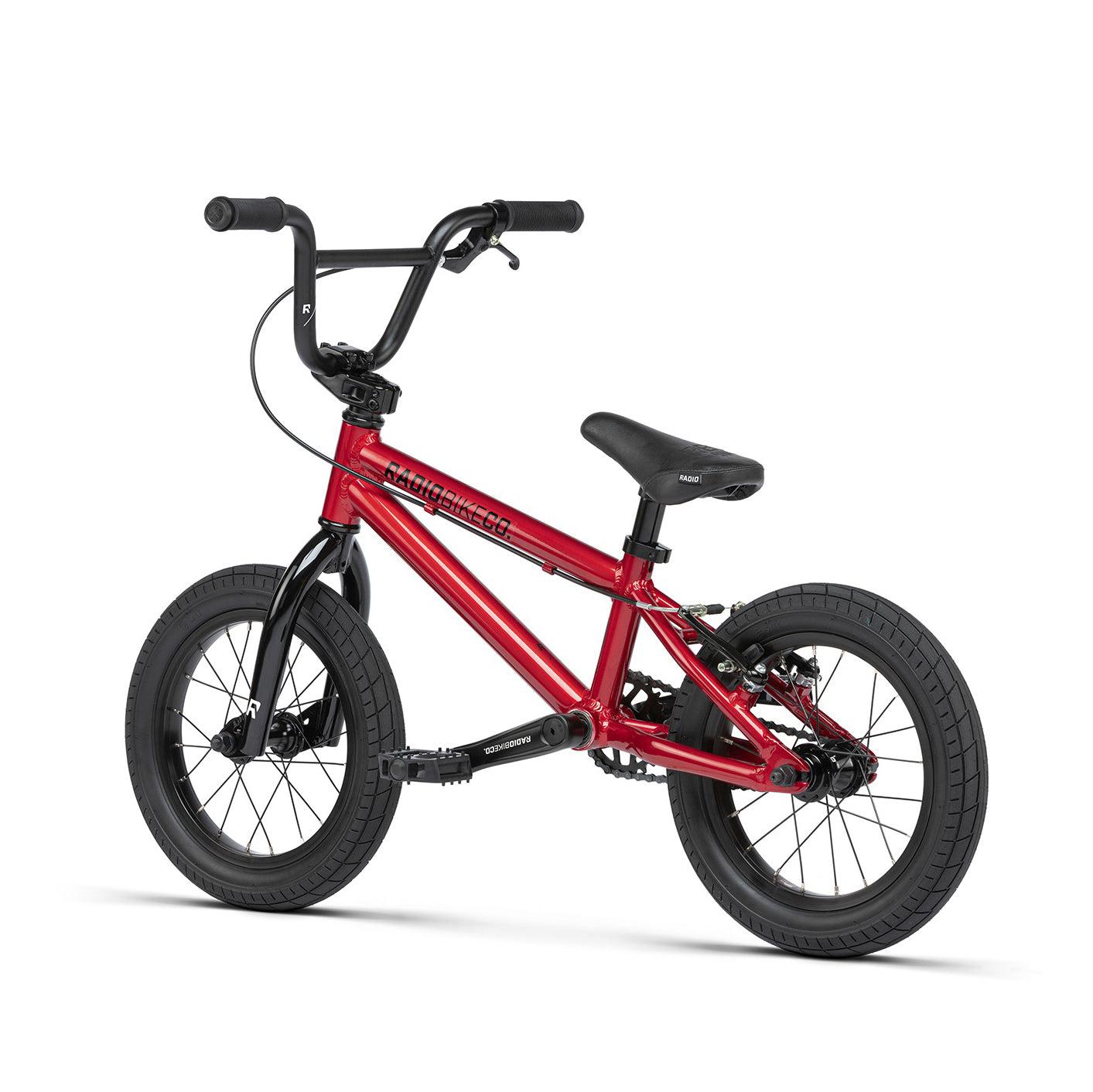 A small, lightweight kids bike with a Radio Dice 14 Inch Bike design, featuring thick black tires, black handlebars, and a black seat. The compact frame is made from 6061-T6 alloy and proudly displays the brand name "Raleigh" on the side.