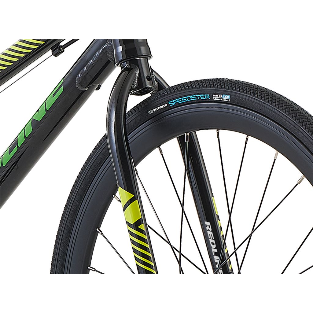 Close-up of the front wheel and fork of a black Redline MX Junior Bike with green decals, featuring a Speedster tire and spokes, highlighting its sturdy aluminum frame designed for BMX racing.