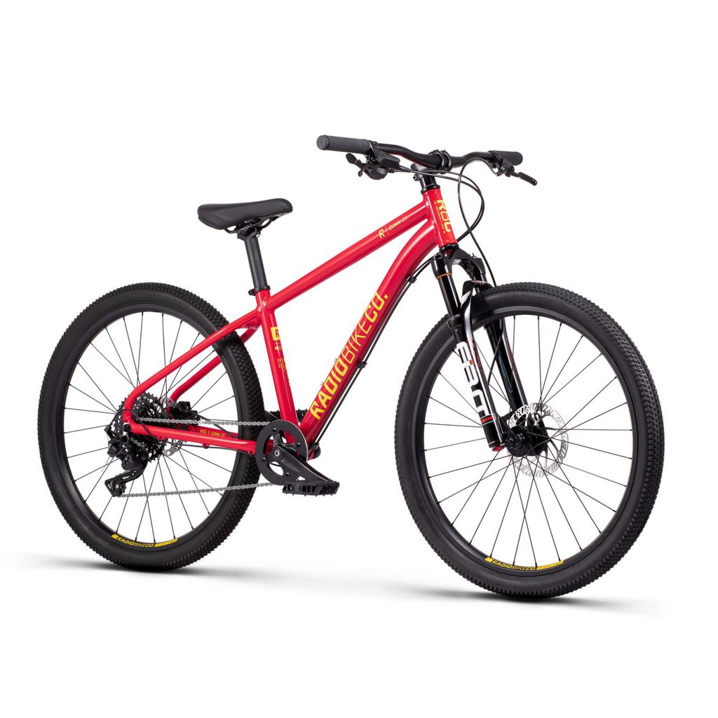 A front suspension, disc brake-equipped hardtail mountain bike with knobby tires, labeled "Radio 26 Inch Zuma Sus Bike" on the lightweight alloy frame, displayed against a white background.