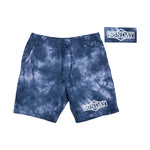 A pair of blue tie-dye Sunday Cornerstone Sweat Shorts with a drawstring waist and pockets. The word "Sunday" is printed on the left leg and appears again in an inset image at the top right. For detailed measurements including inseam and waist inches, refer to our Size Guide.