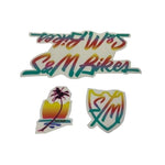 The S&M Hucker Frame Decal Set includes three retro-style designs: "S&M Bikes" text, a shield with "S/M," and a sunset with a palm tree. Ideal for adding charm to your bike frame or as replacement decals.