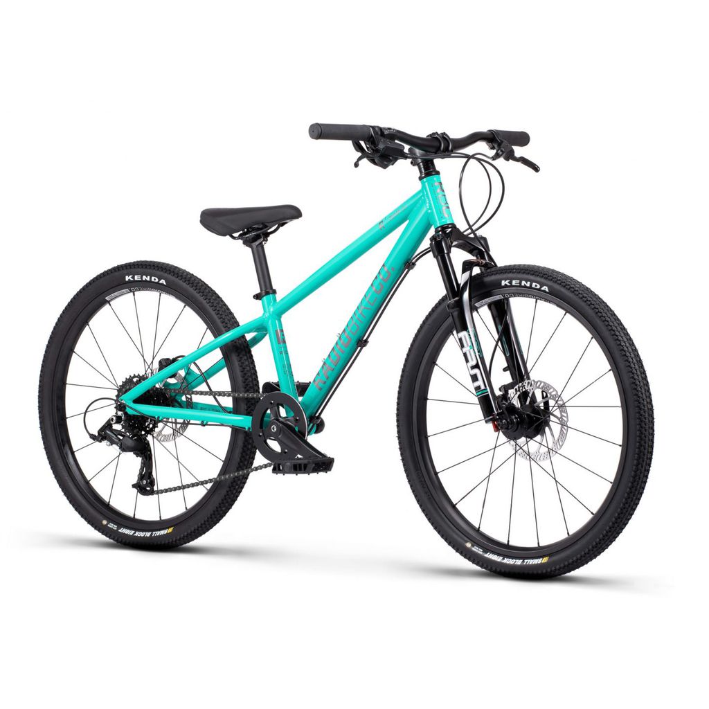 The Radio 24 Inch Zuma Sus Bike is a turquoise kid-sized MTB featuring front Zuma suspension, black handlebars, and black tires. It boasts a sturdy yet lightweight alloy frame and comes equipped with disc brakes and a gear system.