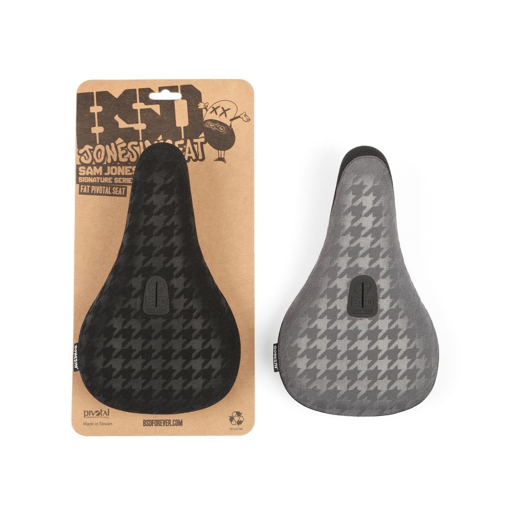 Two bicycle seats in a houndstooth pattern are shown: one black on a display card and the other gray removed from it. The BSD Jonesin Pivotal Seat, featuring Kevlar bumpers, embodies Sam Jones' signature style with its unique design and durability.