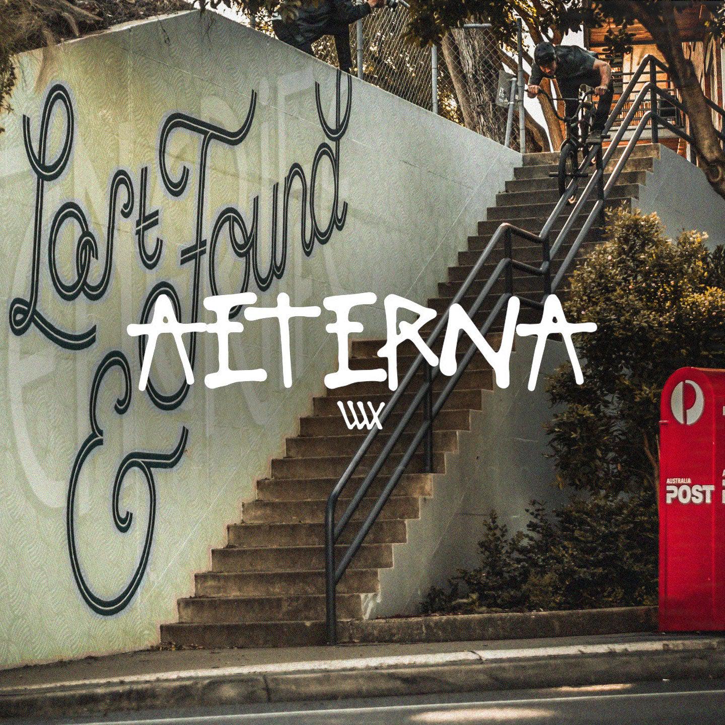 A vibrant street scene features "Lost & Found" graffiti beside the stairs, with a red post box standing prominently to the right—perfectly capturing the essence of a LUXBMX Aeterna Video backdrop.