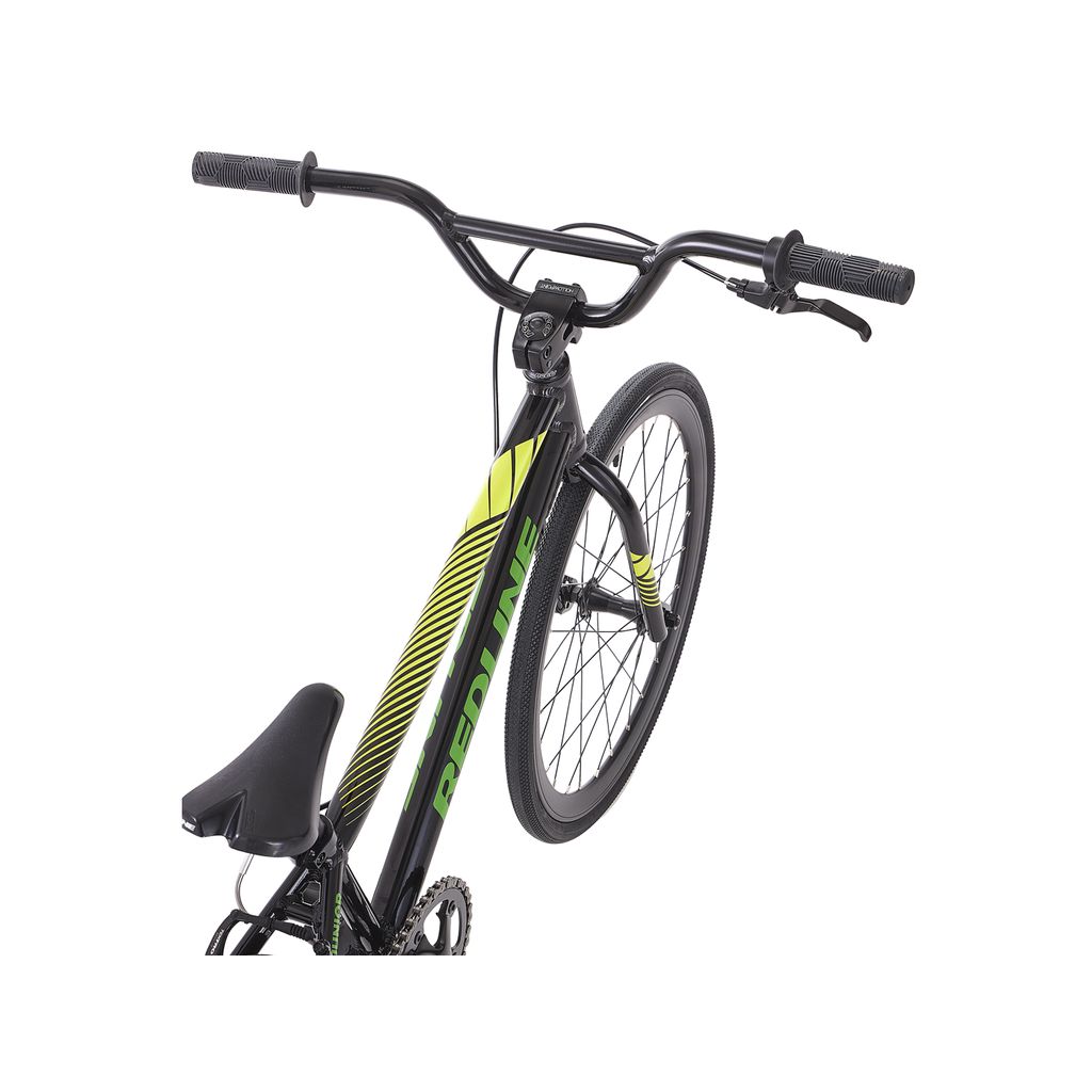 A black and green Redline MX Junior Bike with an aluminum frame, one wheel raised, featuring curved handlebars and a padded saddle.