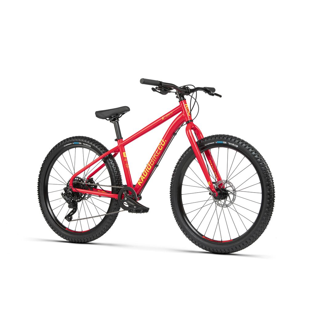 A red hardtail Radio 26 Inch Zuma Bike with black handlebars, seat, and tires, featuring disc brakes and a simple gear system. The kid-sized MTB also boasts a lightweight alloy frame for easy maneuverability.