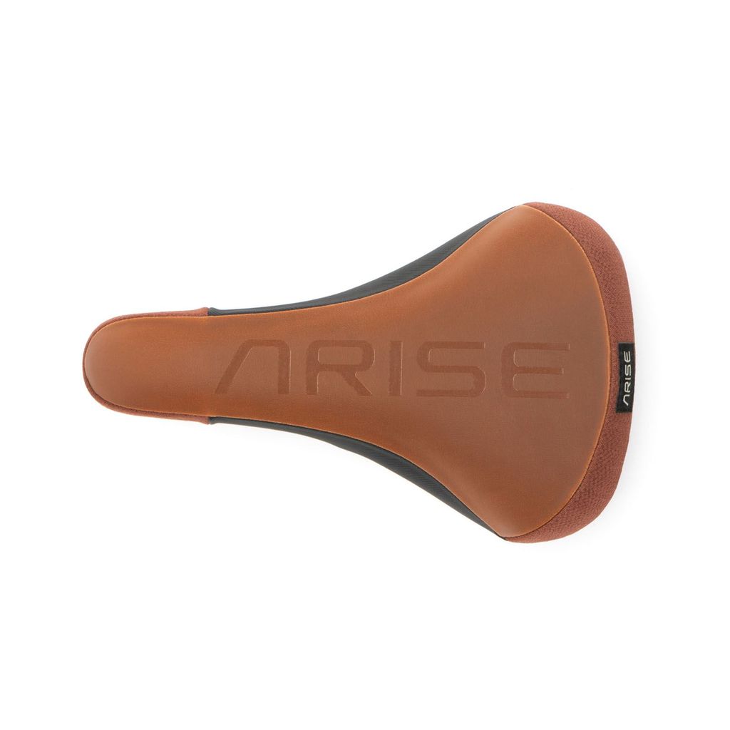 The Arise Sensor Railed Seat is a brown bicycle seat with "ARISE" imprinted and a grippy silicon top for improved traction, ideal for freeride MTB adventures. It offers comfort and style, perfectly captured from above against a pristine white background.