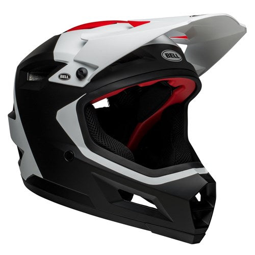 A black, white, and red Bell Sanction 2 DLX MIPS Deft Matte Black is displayed, showcasing its aerodynamic design, visor, ventilation, and protective padding. The brand name "Bell" is visible on the lightweight helmet.
