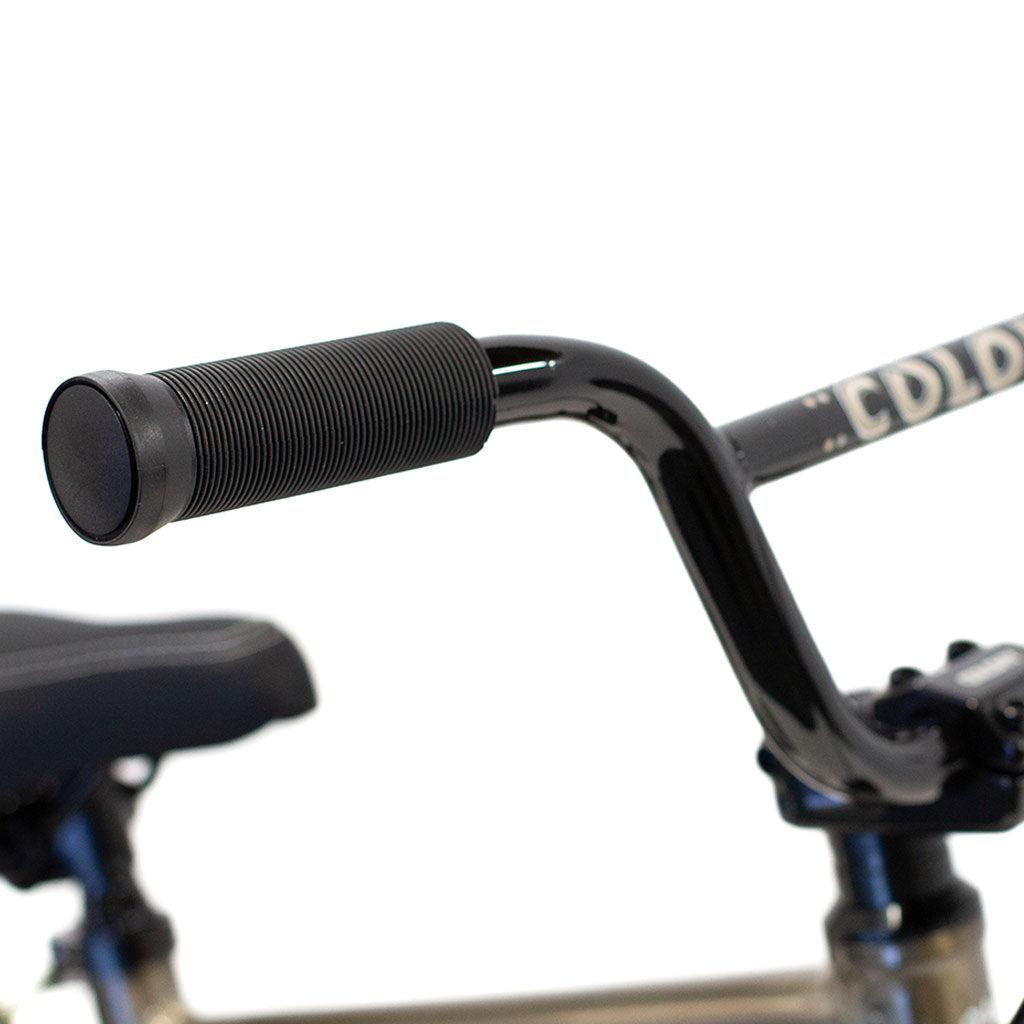 Close-up image of a black handlebar grip attached to a curved handlebar on a BMX bike. Part of the black seat is visible in the background, showcasing the sleek design and durability of the lightweight alloy frame found on a Colony Horizon 12 Inch Bike.