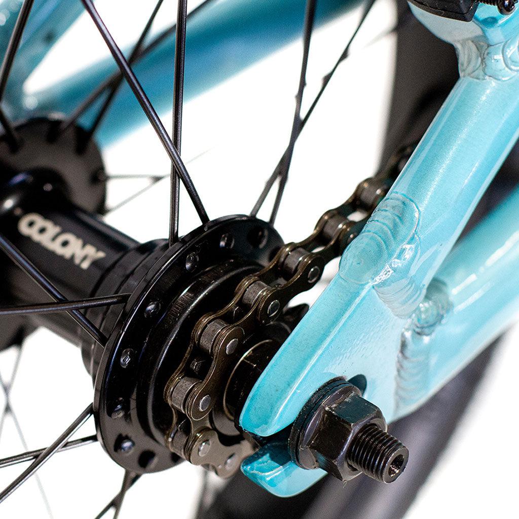 Close-up of the rear wheel hub of a blue Colony Horizon 14 Inch Bike, showcasing the chain and gears against its lightweight alloy frame.