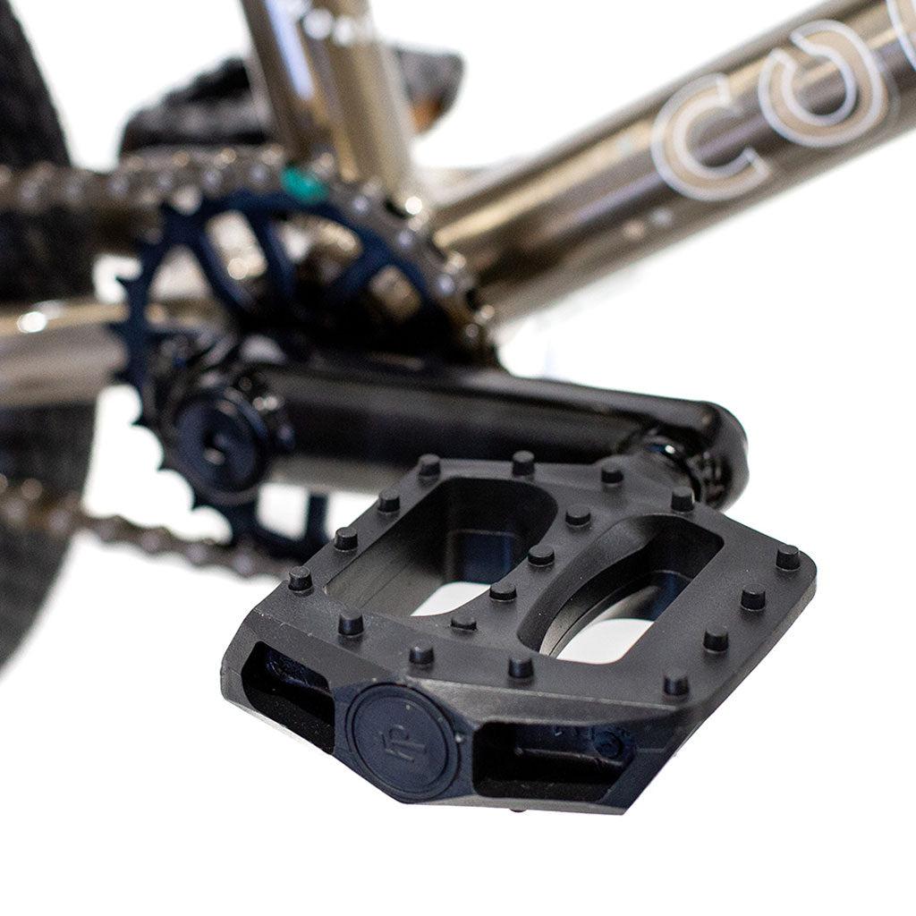 Close-up of a black bicycle pedal attached to the crank arm of a Colony Horizon 14 Inch Bike, with part of the chain and frame visible. Perfect for BMX Freestyle enthusiasts seeking precision and style in every move.