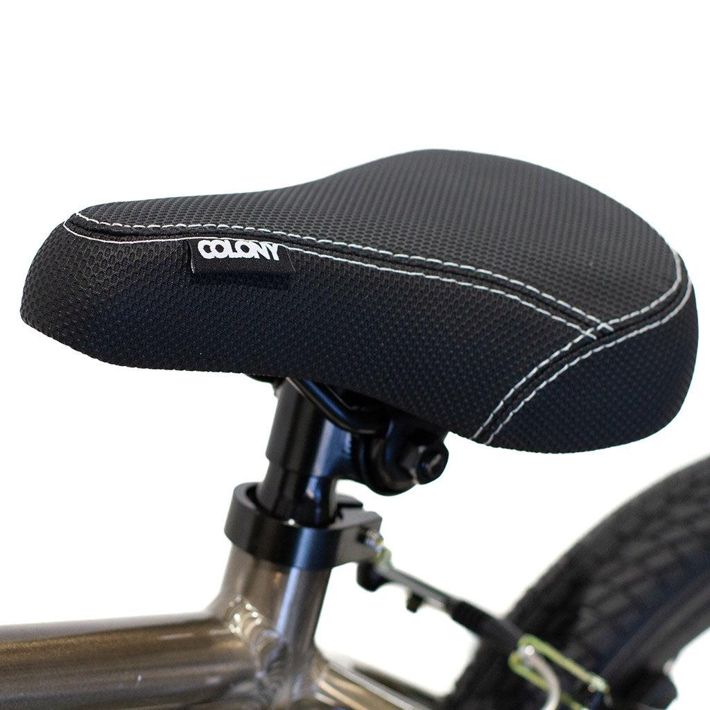 Close-up of a black bicycle seat with white stitching, attached to the lightweight alloy frame of the Colony Horizon 14 Inch Bike, displaying the brand name "COLONY" on a tag.