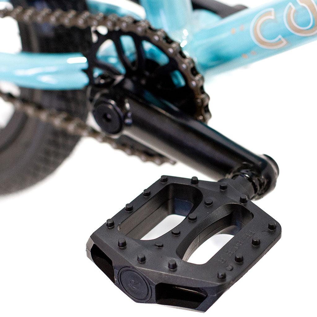 Close-up view of a black bicycle pedal attached to a crank arm on the lightweight alloy frame of a turquoise Colony Horizon 14 Inch Bike.