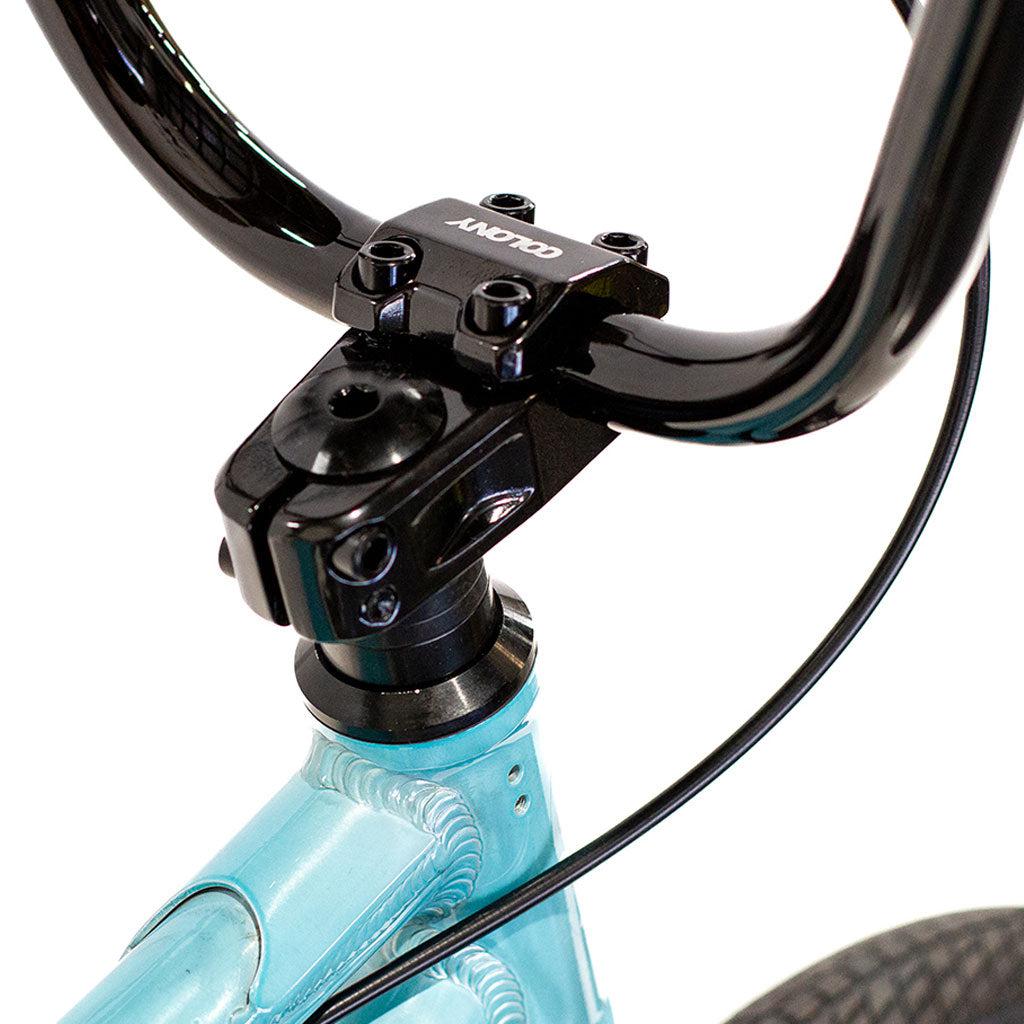 A close-up of a black handlebar and stem connected to a light blue Colony Horizon 20 Inch Freestyle Bike frame, reminiscent of an Olympic athlete's BMX setup.