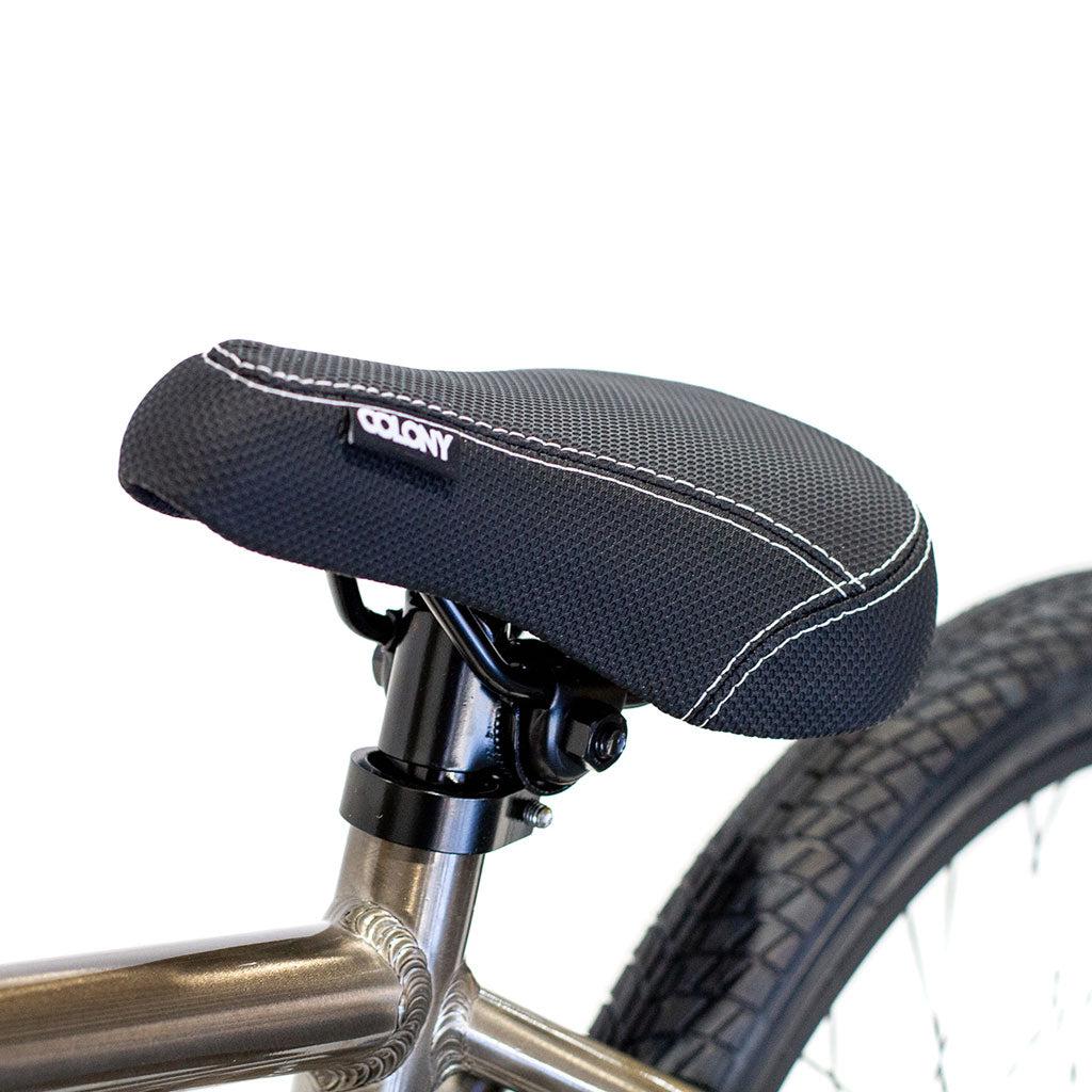 Close-up of the Colony Horizon 20 Inch Freestyle Bike's seat, featuring black padding and white stitching, attached to the bike frame with a portion of the rear tire visible.