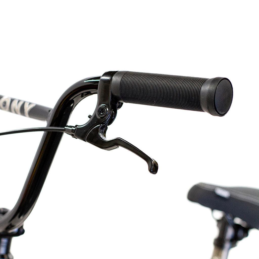 Close-up of the handlebar on a Colony Horizon 20 Inch Freestyle Bike, featuring a brake lever and black rubber grip. The background reveals a blurred section of the bicycle seat.