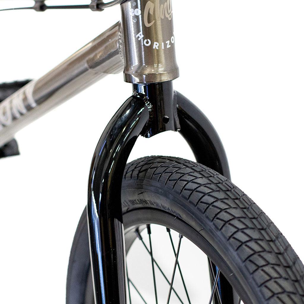 Close-up of a BMX bike front wheel and fork, showcasing the tire tread and the front part of the Colony Horizon 20 Inch Freestyle Bike frame with some branding visible.