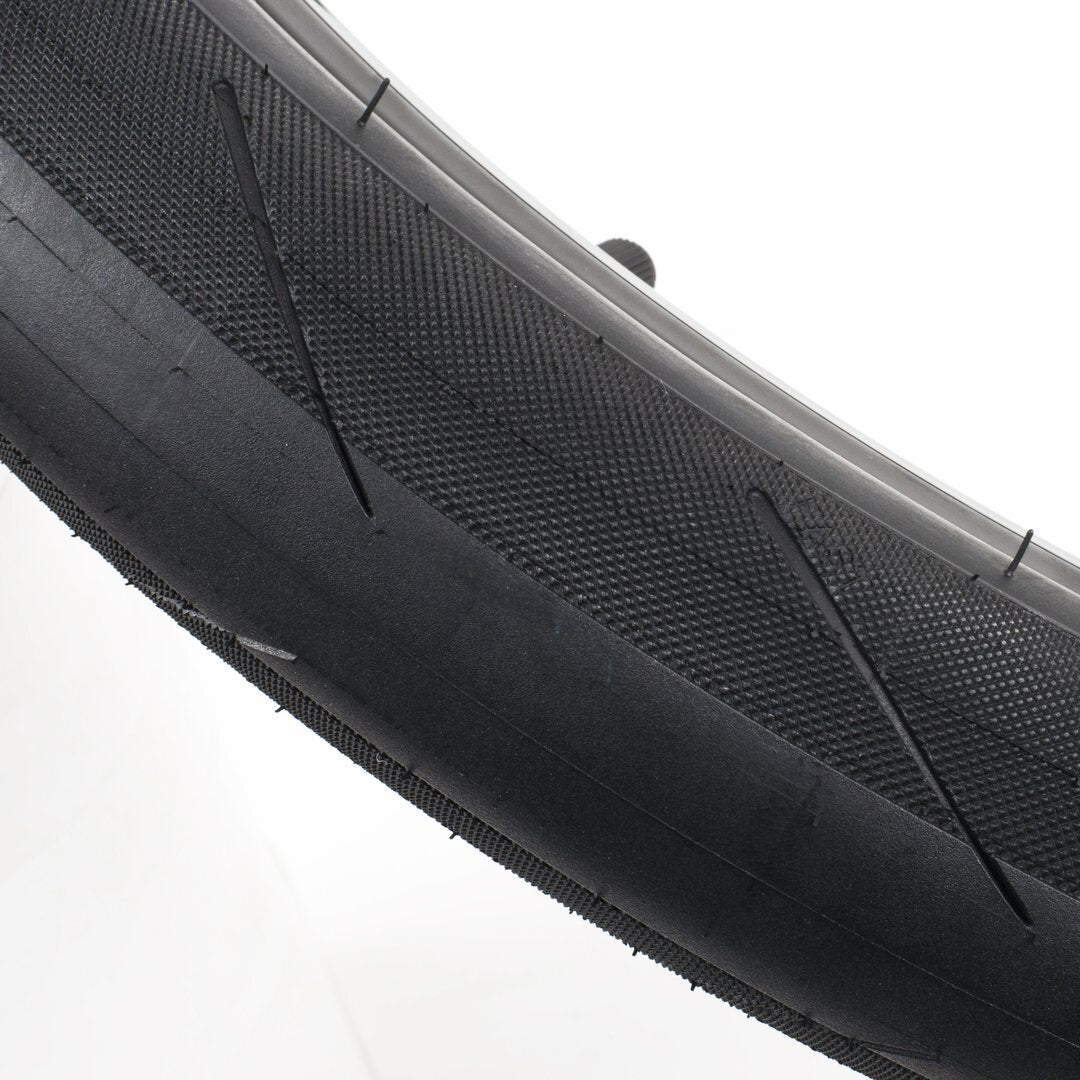 Close-up of the Cult Fast and Loose Pool Tyre, showcasing its detailed tread pattern and high-pressure sidewalls, with a valve stem on a white surface.