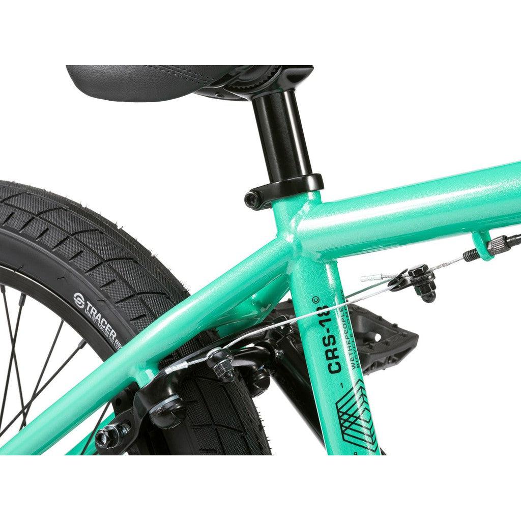 A close-up of a teal Wethepeople CRS FS 18 Inch BMX Bike's seat post, rear wheel, and brake cable captures the essence of freestyle biking, highlighting its sleek features.