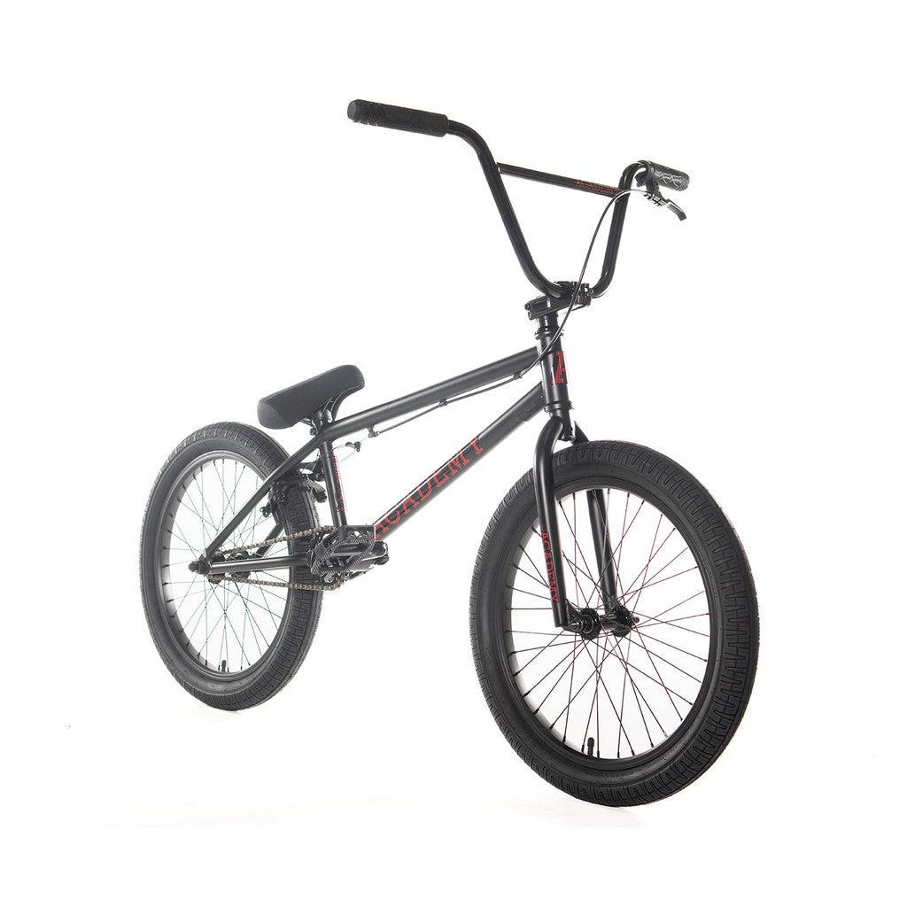 A black Academy Desire 20 Inch Bike with a red and black full Chromoly frame, large tires, and a cushioned seat, photographed against a plain white background. The 21 inch top tube handlebars are wide and the bike is in a side profile view.