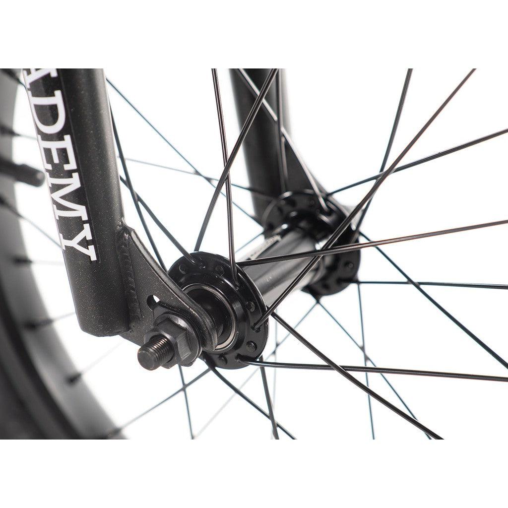 Close-up of the Academy Inspire 16 Inch Bike's wheel hub and spokes, featuring a black fork inscribed with "ACADEMY," illustrating its sturdy CrMo frame.