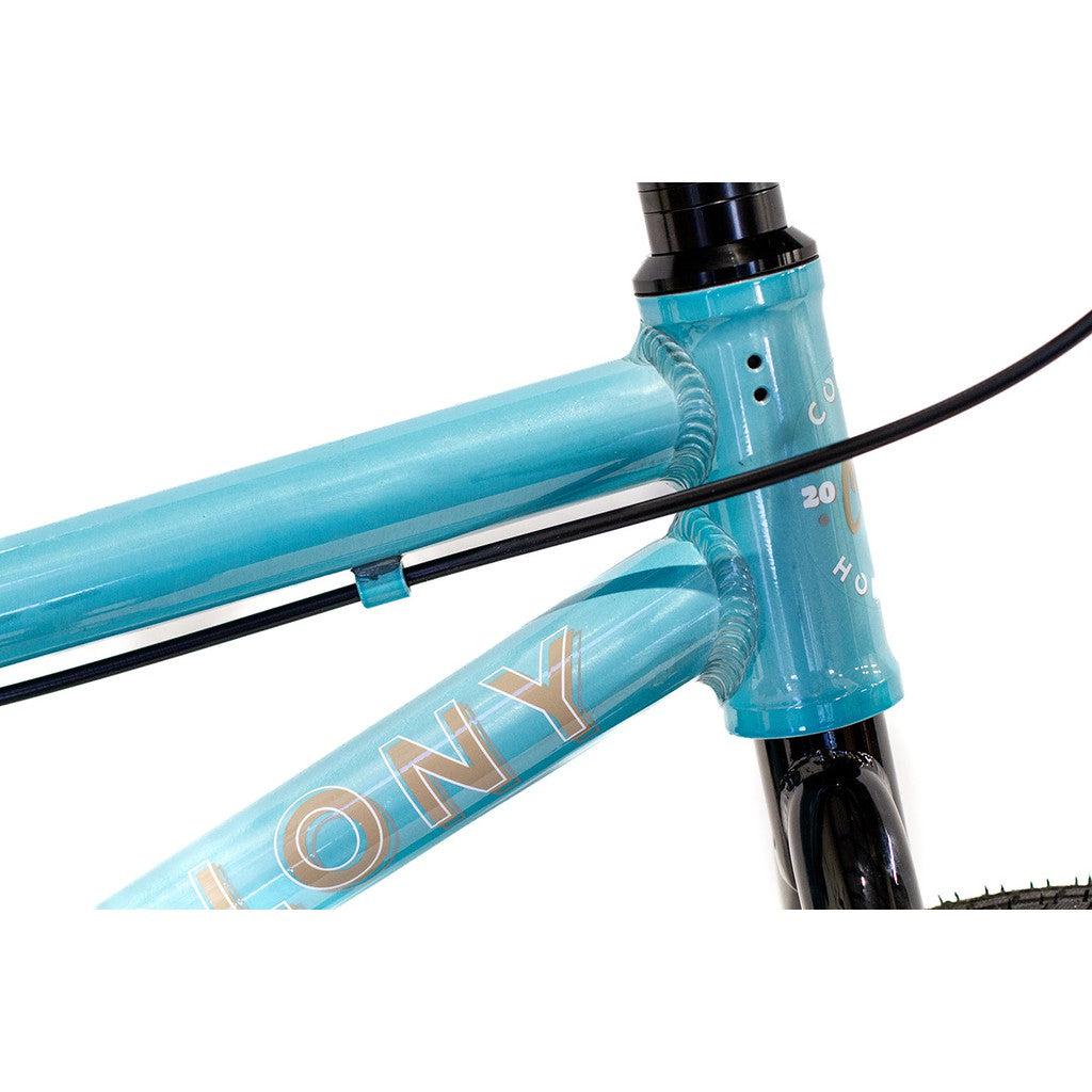 Close-up view of a turquoise BMX bike frame showing the word "COLONY" on the down tube, black cables, and part of the front fork. This Colony Horizon 12 Inch Bike features a lightweight alloy frame for enhanced performance.