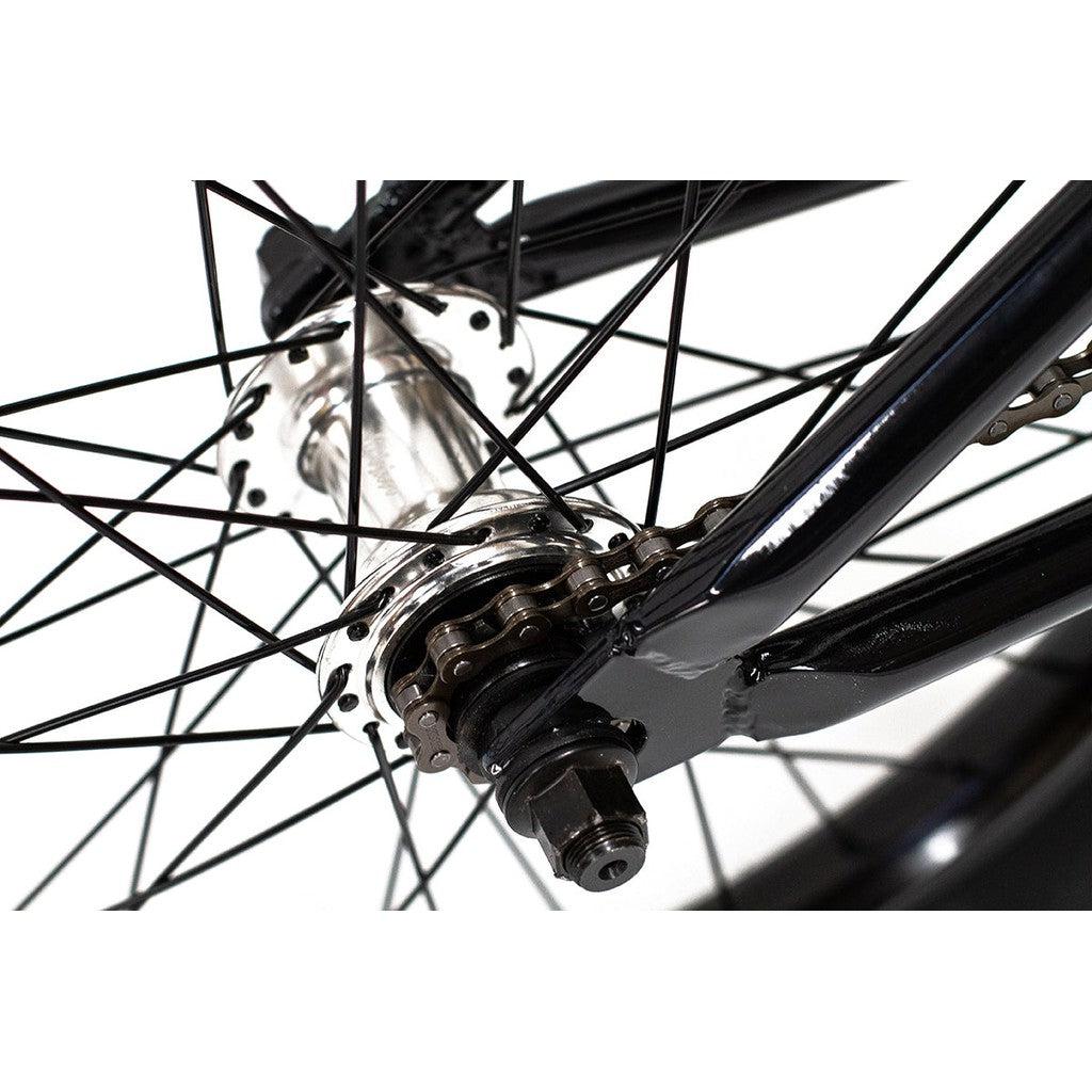 Close-up of the Division Fortiz 20 Inch Bike's rear wheel hub and spokes, showcasing the intricate details of the gear mechanism and axles within a robust black Chromoly frame.