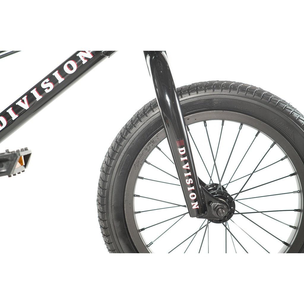 Close-up of the front wheel of a black Division Blitzer 14 Inch BMX bike, highlighting the fork and tire. The word "Division" is printed in white on the fork of this entry-level model, showcasing the intricate spoke design and tread detail.