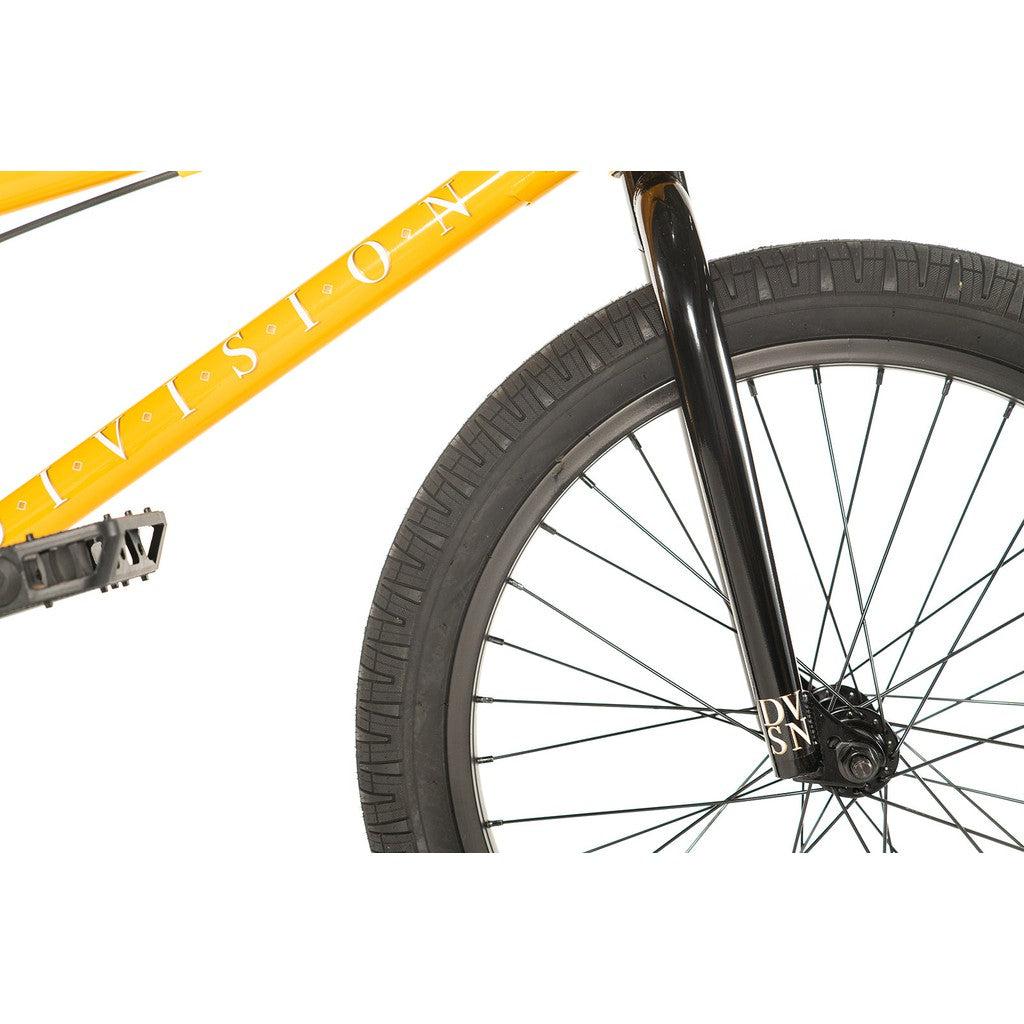 Close-up of a yellow Hi-Tensile steel bicycle frame with black handlebars and tire, showcasing the brand name "Division Reark" on the fork.