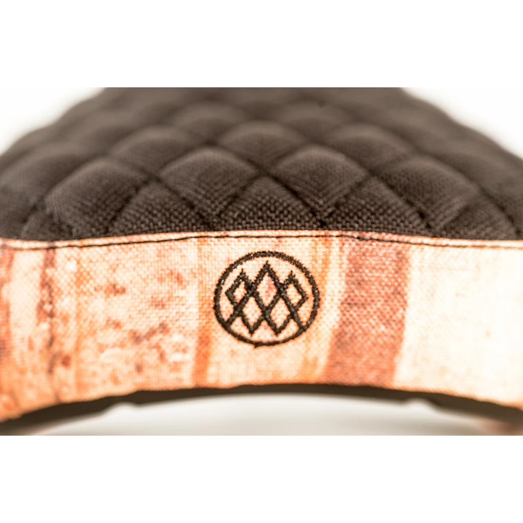 Close-up of black quilted fabric with diamond stitching, featuring a brown band and a black geometric logo with interlocking diamonds, reminiscent of the Colony Wallwork Pivotal Seat design.